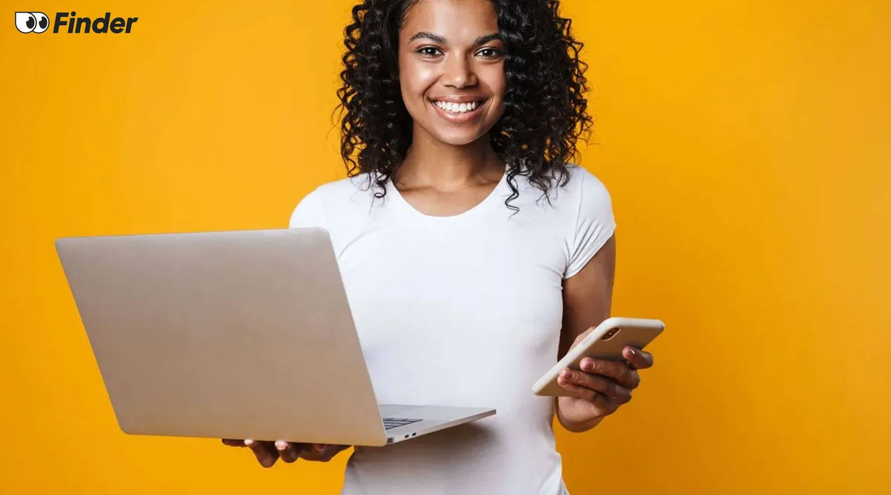 Smiling woman holding a laptop and a smartphone
